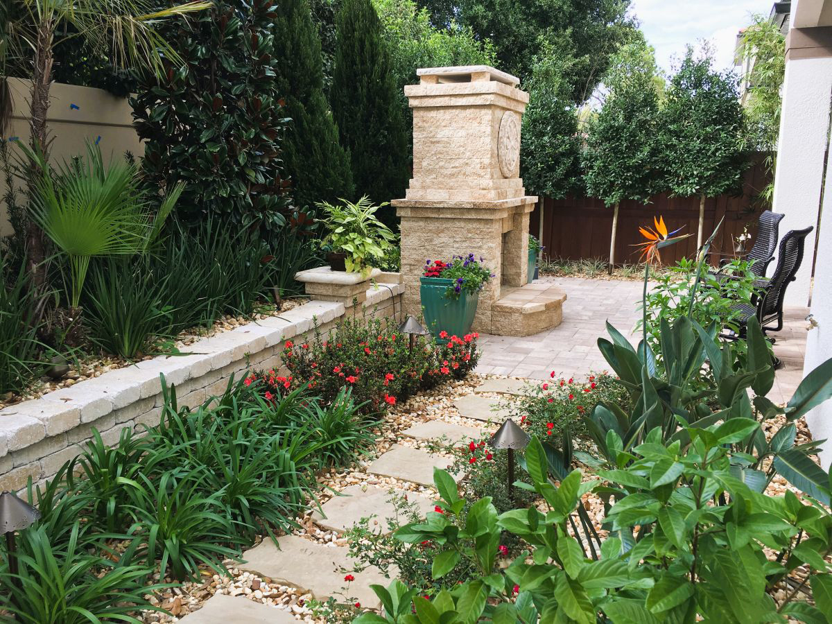 Backyard design for an Orlando estate home featuring a structured patio layout, stone fire feature, and layered landscape planting