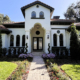 Mediterranean-style Orlando home with a landscaped front entrance, brick paver walkway, flowering garden beds, mature trees, and landscape lighting.