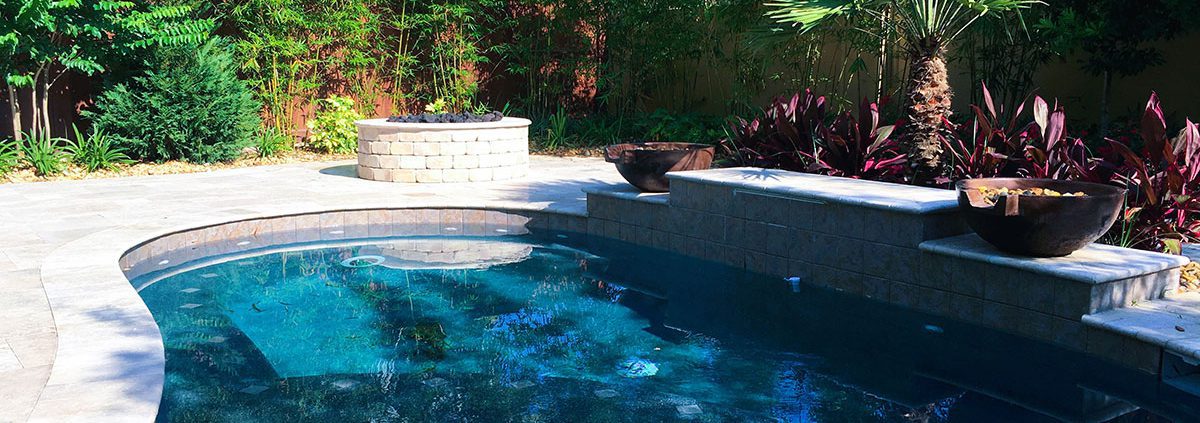 Orlando estate backyard pool with privacy landscaping, tropical palms, stone retaining wall, and integrated patio design