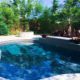 Orlando estate backyard pool with privacy landscaping, tropical palms, stone retaining wall, and integrated patio design