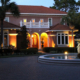 Outdoor lighting illuminating a luxury home's entrance, palm trees, landscaping, and courtyard fountain. Orlando Landscape Design by BLG Environmental Services
