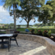 Paver patio with outdoor dining furniture, curved stone planter walls, mature trees, and a lakefront view in the Orlando Florida area.