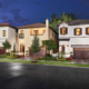 File Name:\ `orlando-residential-landscape-design-evening-lighting.jpg` Alt Tag:\ `Orlando residential landscape design featuring three Mediterranean-style homes with manicured lawns, palm trees, ornamental plantings, and landscape lighting at dusk.`